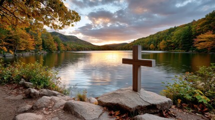 A rustic cross by a tranquil mountain lake, with autumn foliage in warm sunset hues.