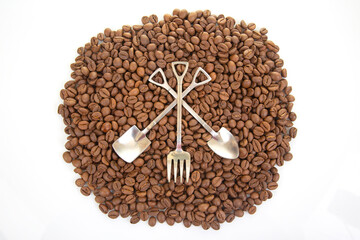 Elegant still life featuring two crossed metal shovels surrounded by roasted coffee beans, great for coffee brand promotions or rustic decor
