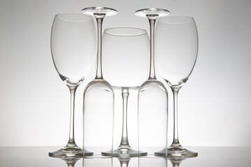 Five refined wine glasses with varied designs, their reflections shimmering on a reflective surface, ideal for wine culture or elegant interior photography.