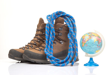 Trekking boots for hiking next to a world globe model on a white background. Equipment for travel and hiking