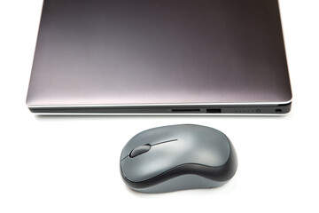 Computer wireless mouse next to a laptop on a white table close-up. electronic personal industry