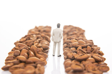 Creative stock image of a tiny figure in a suit walking amidst coffee beans, symbolizing a professional journey in coffee commerce