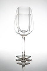 A sleek lineup of three elegant, empty wine glasses with long stems, reflecting on a glossy surface against a soft gray background, perfect for dining or event themes.