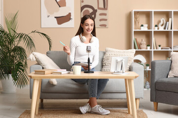 Young woman with notebook recording podcast at home