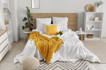 Interior of light bedroom with bed, shelf units and lemons