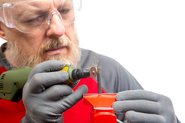 A skilled craftsman in safety goggles focuses intently on a rotary tool as he grinds a metal object, sparks flying in a bright workshop environment. work of a mechanic in a workshop.