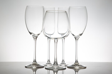 Fototapeta premium Elegant wine glasses with long stems and clear bowls, arranged in a line with reflections on a shiny surface, perfect for luxury dining or celebration themes.