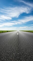 Fototapeta premium Empty asphalt road stretches toward the distant horizon under a bright blue sky with wispy white clouds. Perfect background for travel concepts ,distance ,journey ,texture