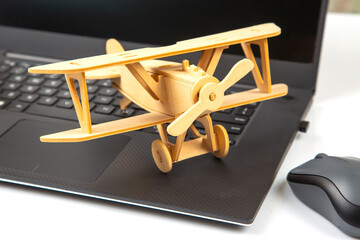 Model of a wooden plane on the background of a laptop. Business development and success. Dream to fly in your favorite business.