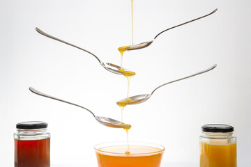 Fresh flower honey drips from a spoon into a spoon on a white background. Organic vitamin food.