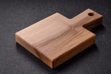 Wood, a wooden empty cutting board on a dark kitchen table. Wooden cutting board