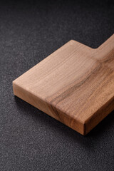 Wood, a wooden empty cutting board on a dark kitchen table. Wooden cutting board