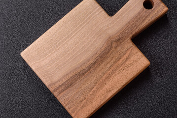 Wood, a wooden empty cutting board on a dark kitchen table. Wooden cutting board