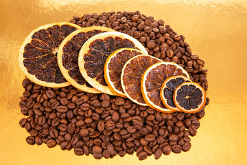 Golden reflective surface hosts coffee beans and dried orange slices, a perfect shot for aromatic food compositions. coffee aroma and taste citrus descriptors