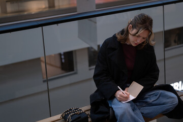 Young woman focused on writing in notebook while sitting indoors