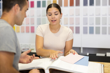 Obraz premium Female seller of the hardware store advises man of the buyer what color to choose for ceramic tiles