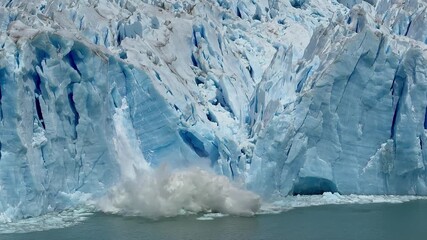 A huge ice mass at Argentina Patagonia Lake Argentino Perito Moreno glacier breaks off and crashes into the water, showing powerful natural movement and impact