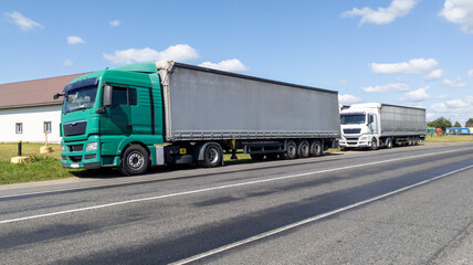 Two large trucks parked on the side of a rural road. Side view. Cargo transportation concept.