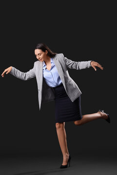 Businesswoman in pose of marionette on dark background