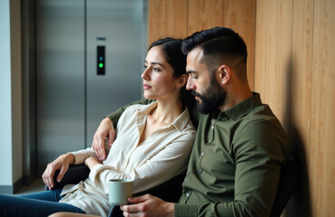 Man and woman relaxing in a modern lounge with warm wood paneling and coffee