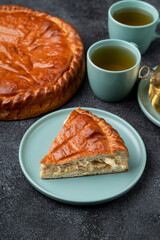 A perfectly baked golden pastry, sliced to reveal its tasty filling, sits on a soft blue plate. Two cups of steaming tea await beside it, creating a warm and inviting atmosphere for sharing
