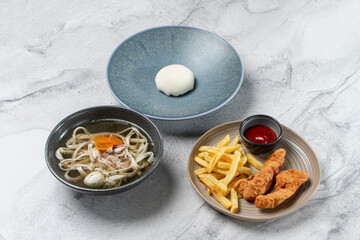 A colorful array of food showcases a warm bowl of soup with noodles, a side of crispy fries, and tender chicken strips, creating a comforting culinary delight