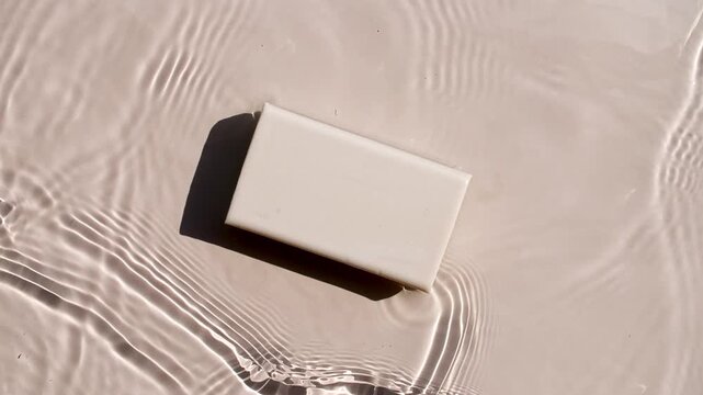 A bar of soap on a water surface. Splash of water, sunlight and shadows. Concept of bath products, skin care products advertisement spa cosmetics and relaxation. Medical body care. High quality 4k 
