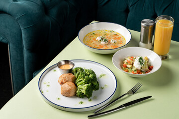 A delightful brunch showcases tender broccoli, savory dumplings, a hearty soup, and a refreshing fruit salad. The setting feels warm and inviting, perfect for enjoying a meal with friends