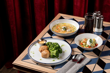 A welcoming restaurant table holds a vibrant meal filled with broccoli, savory side dishes, and a refreshing salad, inviting diners to enjoy a satisfying lunch experience
