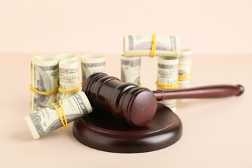 Judge's gavel with dollar banknotes on beige background, closeup