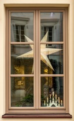 Window with a Scandinavian star ornament hanging beside an elegant candleholder, creating a warm and cozy interior atmosphere