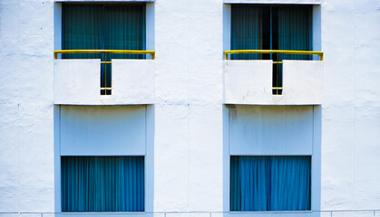 Front view of a tall hotel building with a bright blue cloudy sky in the background. Window hotel with vintage design in center of the town. Hotel at the city metropolitan concept