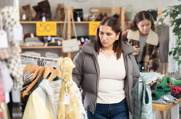 Female shopper selects some fall winter outerwear at a clothing store