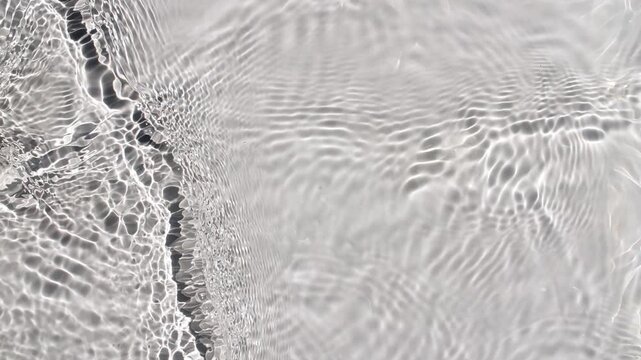 Pure water with reflections sunlight in slow motion. Water surface texture top view. Sun and shadows. Motion clean swimming pool ripples and wave. High quality 4k footage