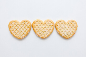 Three heart-shaped sugar cookies on white background, top view