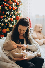 Mother holding newborn baby celebrating first christmas