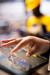 Closeup of technician leveraging a digital app to enhance solar energy output. Selective focus on factory specialist using tablet, supervising smart machinery used in solar panel production.