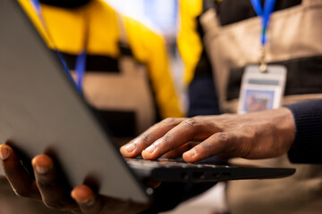Selective focus of engineers inputting industry 4.0 software data to optimize solar panel production. Closeup of african american technicians upgrading automation system on laptop in industrial plant.