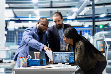 Multiethnic team of technicians collaborating in a solar panel power plant, reviewing blueprints and sharing ideas to enhance renewable energy production and sustainable innovation.