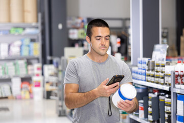 Male shopper scanning a QR code using a mobile phone in a hardware store