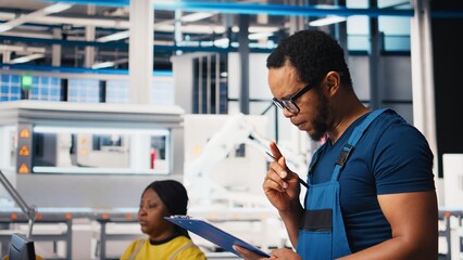 Portrait of engineer in photovoltaics factory reviewing paperwork to diagnose malfunctioning systems. Solar panels plant worker reading inspection data files to reduce downtime. Camera B.