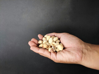 Hand holding pistachio nuts on a black background