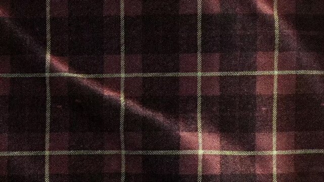 A close-up of a flannel fabric with a plaid pattern in dark and light colors.