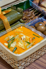 Indonesian Sayur Lodeh Jipan coconut vegetable curry served in a woven bamboo hamper, with lontong, braised eggs and grilled satay in the background.