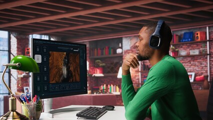 African American person uses AI chatbot to generate a video montage at home office, deep learning models and cloud technology for a personalized project, text to video. Camera B.