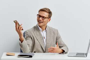 smiling young caucasian man hold smartphone sit at desk work laptop digital nomad concept video call remote communication