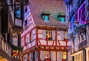 Obraz premium Christmas decorations on half timbered houses in Colmar, France glow at sunset