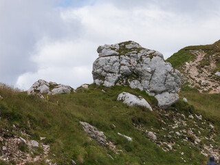 Epic alpine mountains landscape of the Mangart massive rugged cliffs with atmospheric light from the cloudy sky 