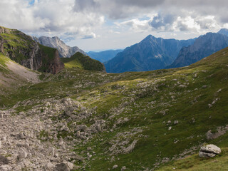 Epic alpine mountains landscape of the Mangart massive rugged cliffs with atmospheric light from the cloudy sky 