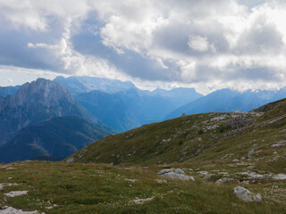 Epic alpine mountains landscape of the Mangart massive rugged cliffs with atmospheric light from the cloudy sky 